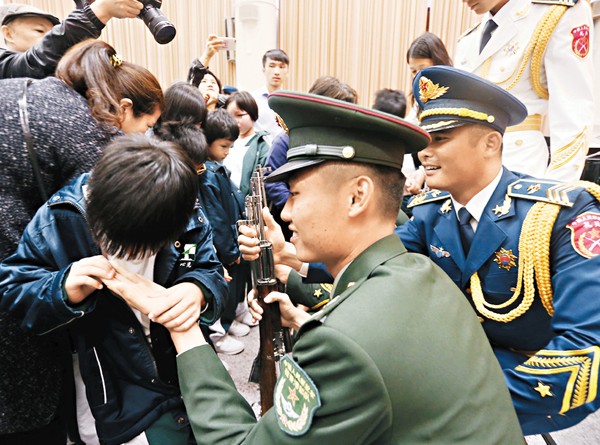 駐軍探訪心光盲人學校，一眾官兵不但俯下身與他們聊天，又讓學生觸摸制服勳章，圖為一小童撫摸官兵手。莫雪芝 攝