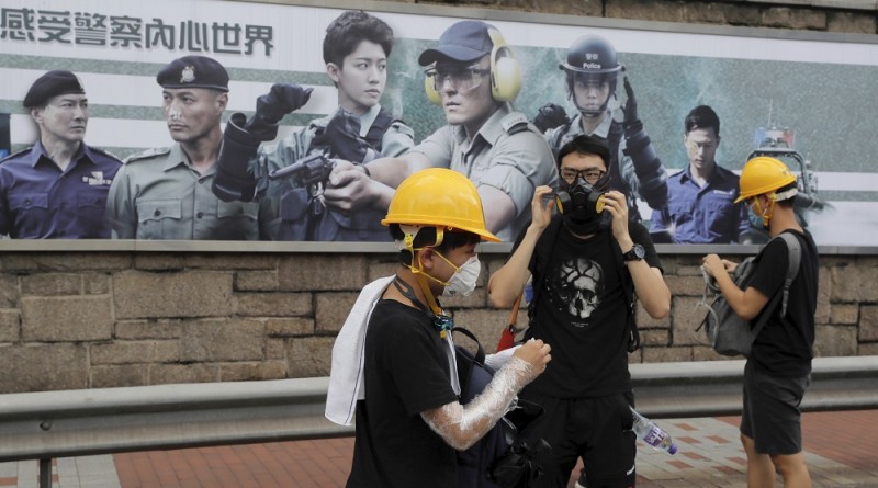 Protesters prepare protection gears as they gather near a poster with the words "Experience the inner world of the police" outside the police headquarters in Hong Kong Friday, June 21, 2019. Several hundred mainly student protesters gathered outside Hong Kong government offices Friday morning, with some blocking traffic on a major thoroughfare, after a deadline passed for meeting their demands related to controversial extradition legislation that many see as eroding the territory's judicial independence. (AP Photo/Kin Cheung)