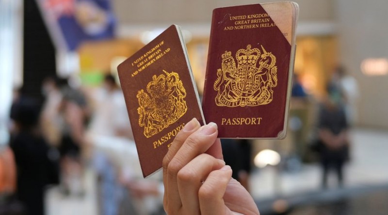FILE PHOTO: A pro-democracy demonstrator raises his British National Overseas (BNO) passports during a protest against new national security legislation in Hong Kong, China June 1, 2020. REUTERS/Tyrone Siu/File Photo